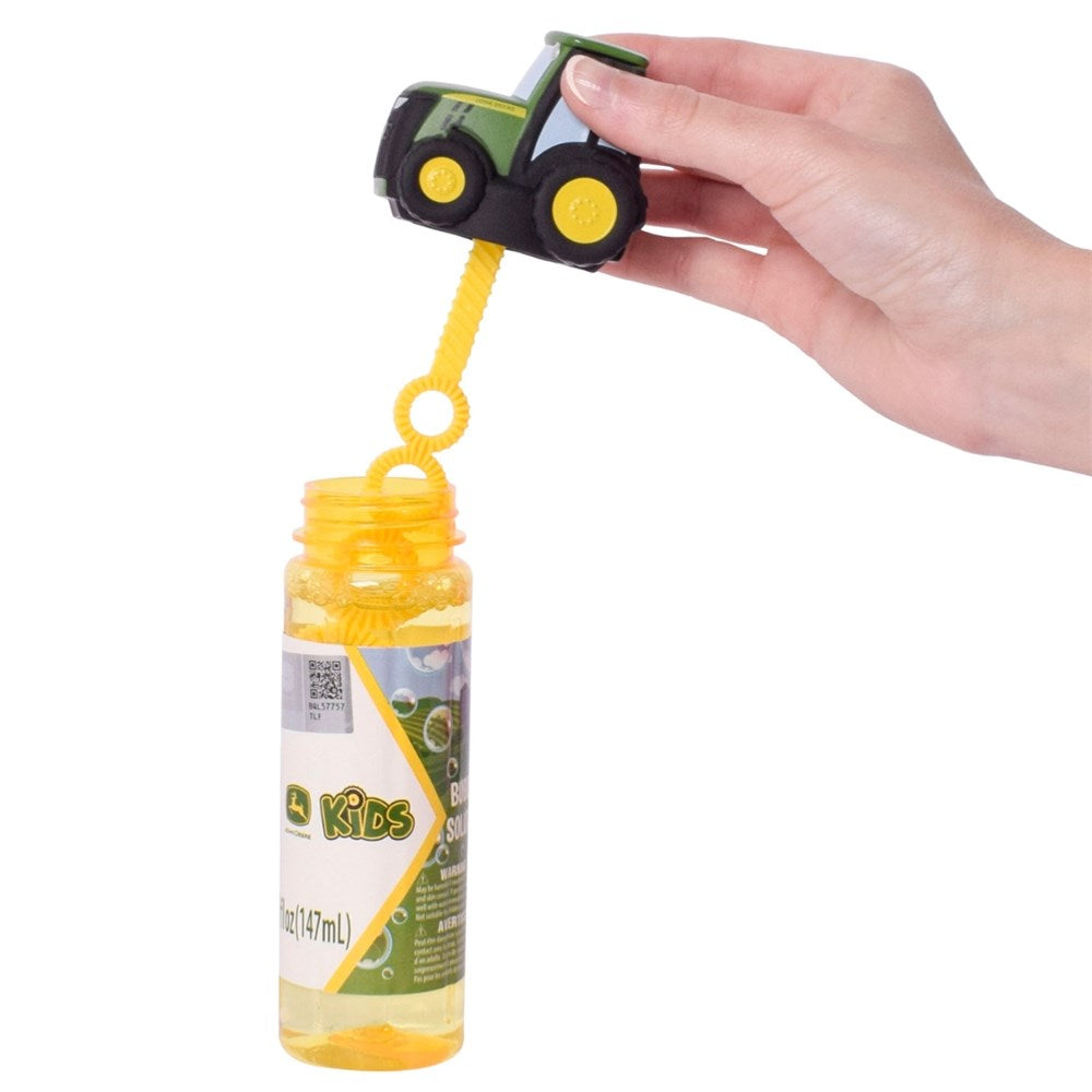 John Deere Tractor Top Bubble Solution 147ml Bottle. Hand holding a toy truck over a bubble bottle labeled 'Kids' on a white background