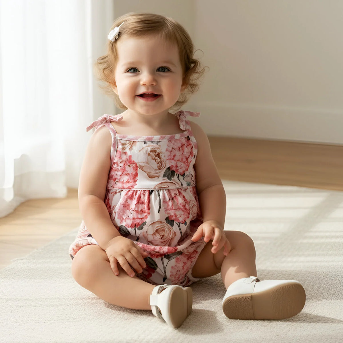 Baby sitting on a light-colored rug in a softly lit room.