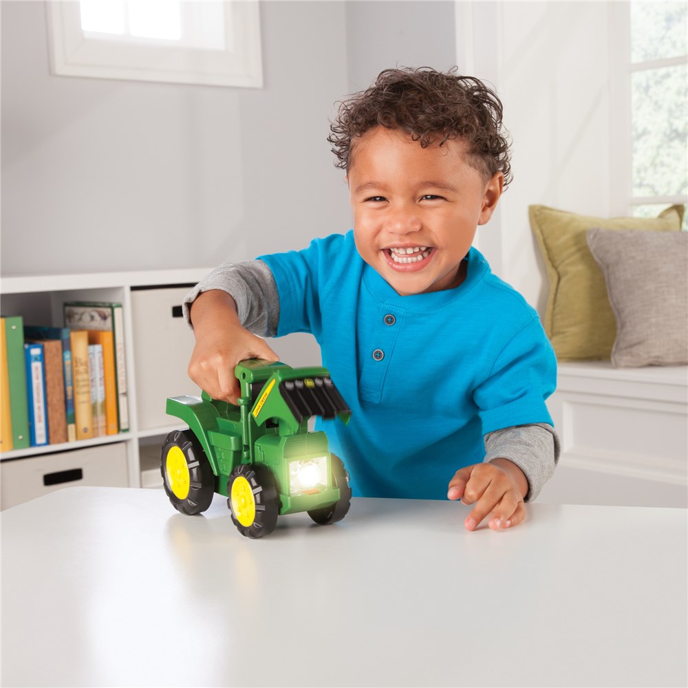 John Deere Tractor Torch . Child playing with a toy tractor indoors