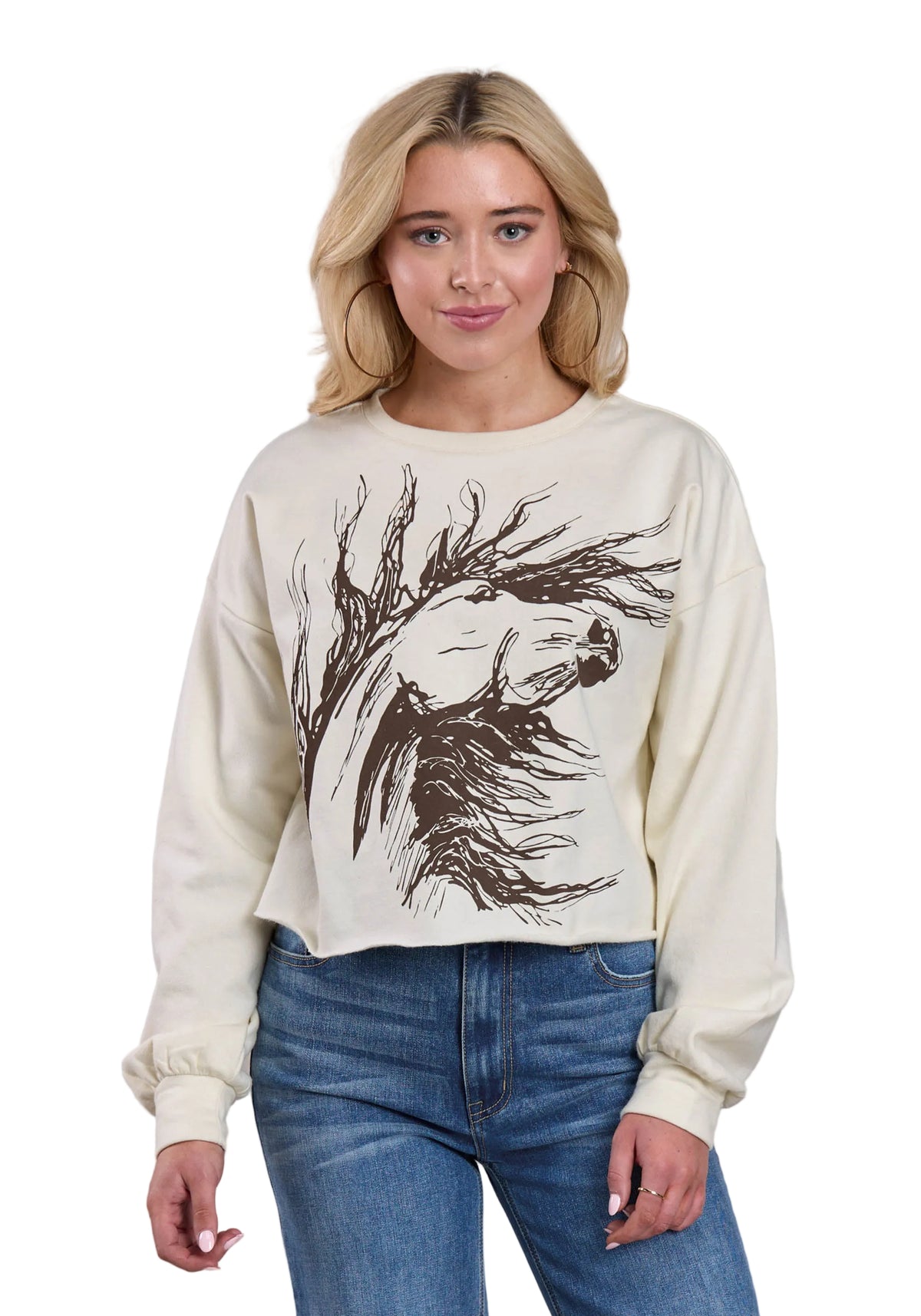 Woman wearing a cream sweatshirt with a black graphic design on a plain background