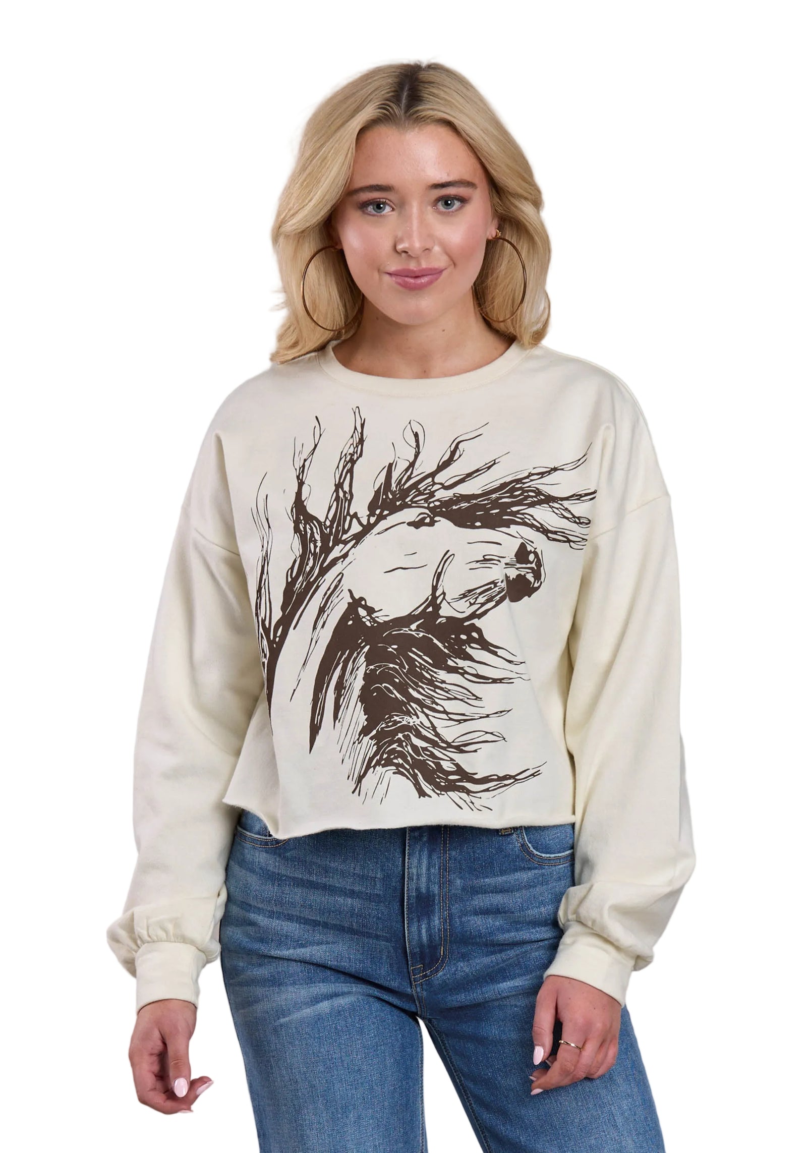 Woman wearing a cream sweatshirt with a black graphic design on a plain background