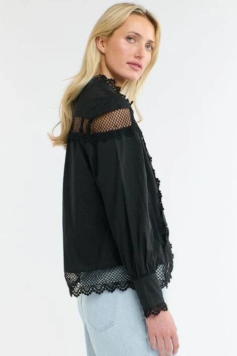 Woman wearing a 365 Women's Victoria Blouse. Black lace-trimmed  with light blue jeans on a white background