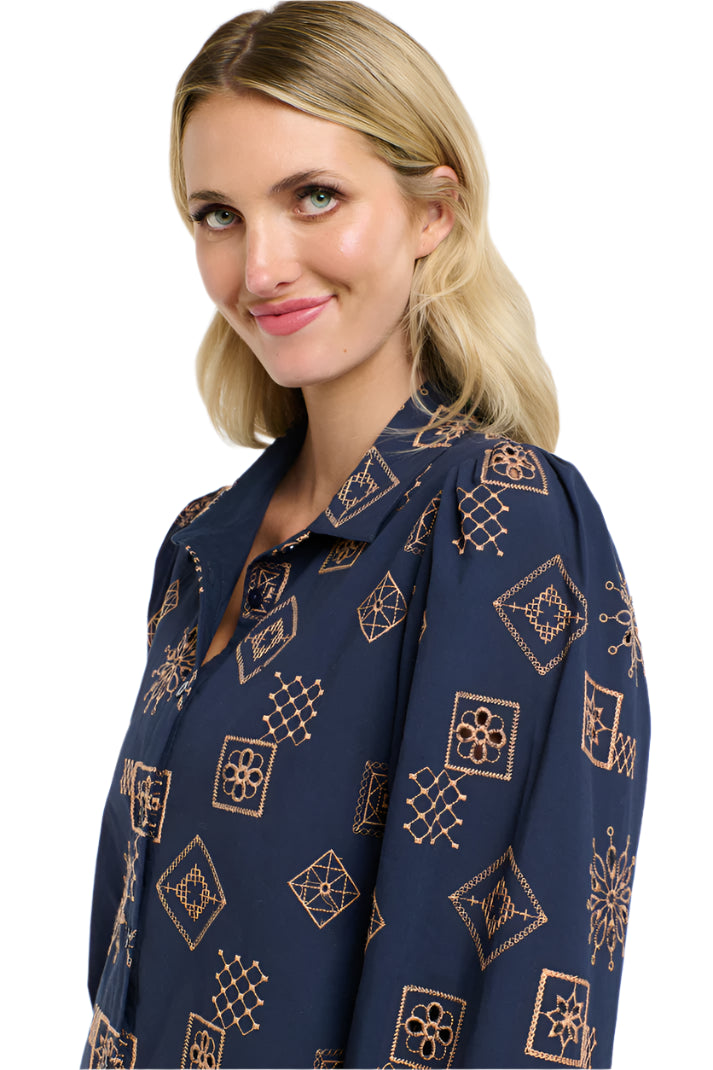 Close up of a woman wearing a 365 Women's Mandala Blouse dark blue patterned blouse with a plain background