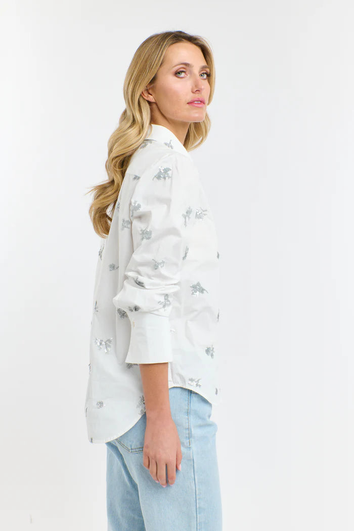Woman wearing a white floral blouse and light blue jeans on a white background