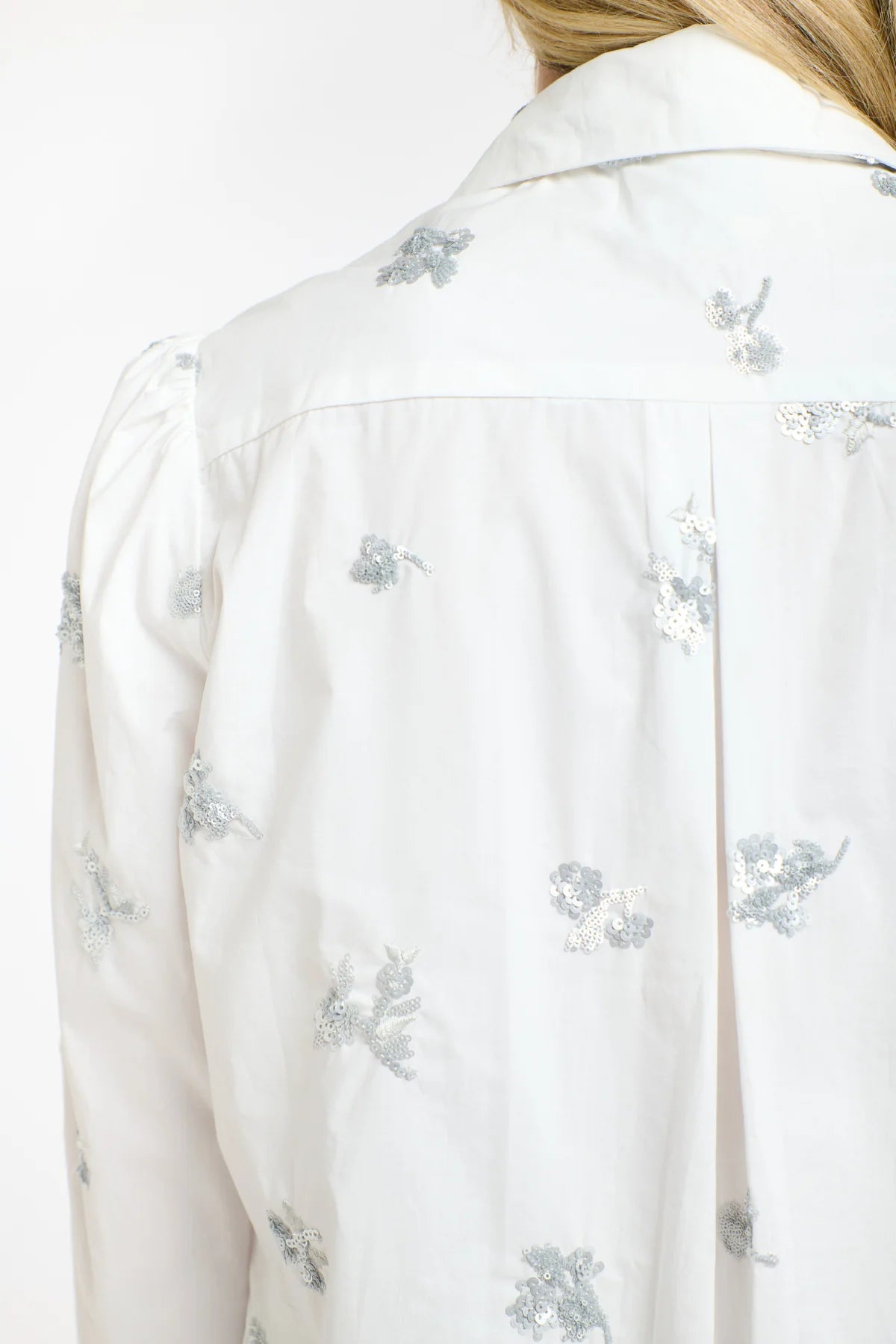 Woman wearing a 365 Women's Penelope Sequins Shirt. A light gray sweater over a white shirt with a plain background. 