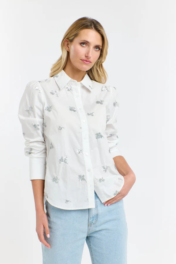Woman wearing a white floral blouse and light blue jeans on a white background