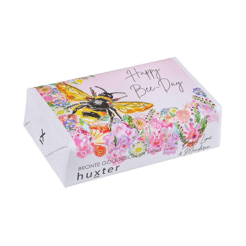 Huxter BG Happy Bee Day Soap. A packaged bar of soap with a floral design and an illustration of a bee, with the text 'Happy Bee Day' on the top.