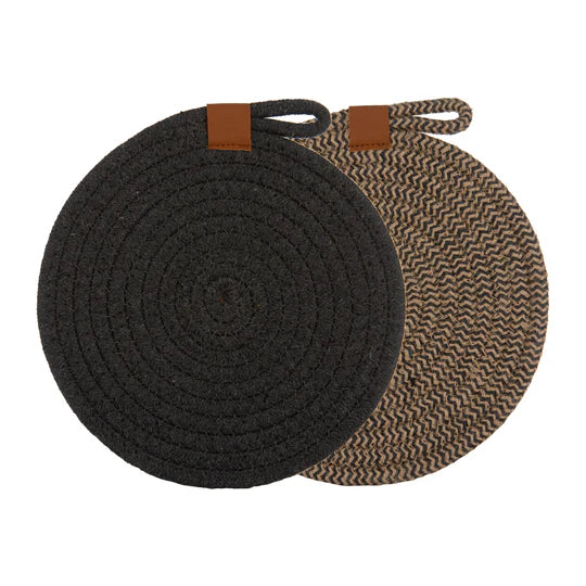 Nash Charcoal Set of 2 Trivets. Two round woven trivets, one black and one brown, with brown leather straps on a white background.