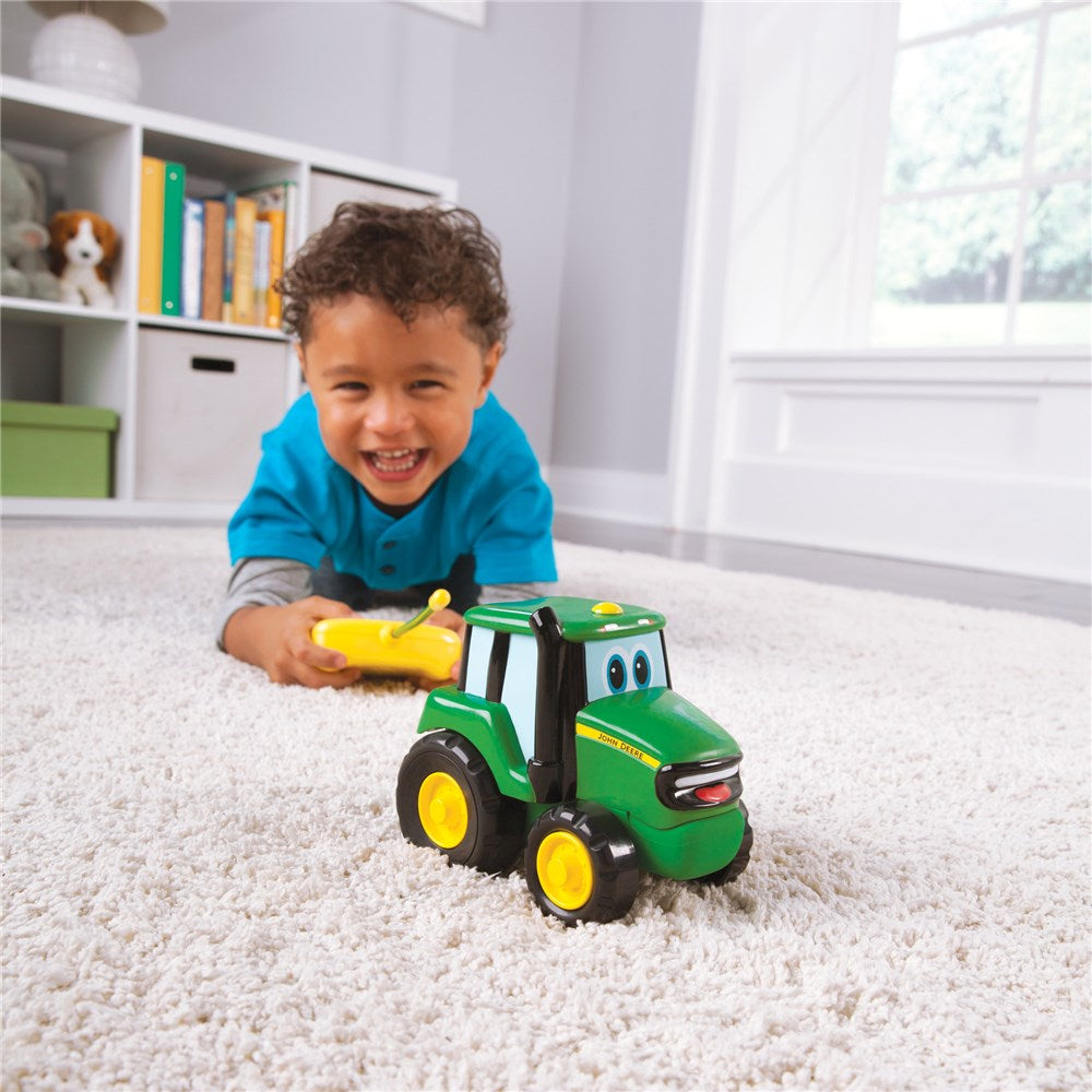 Child playing with a toy tractor on a carpeted floor