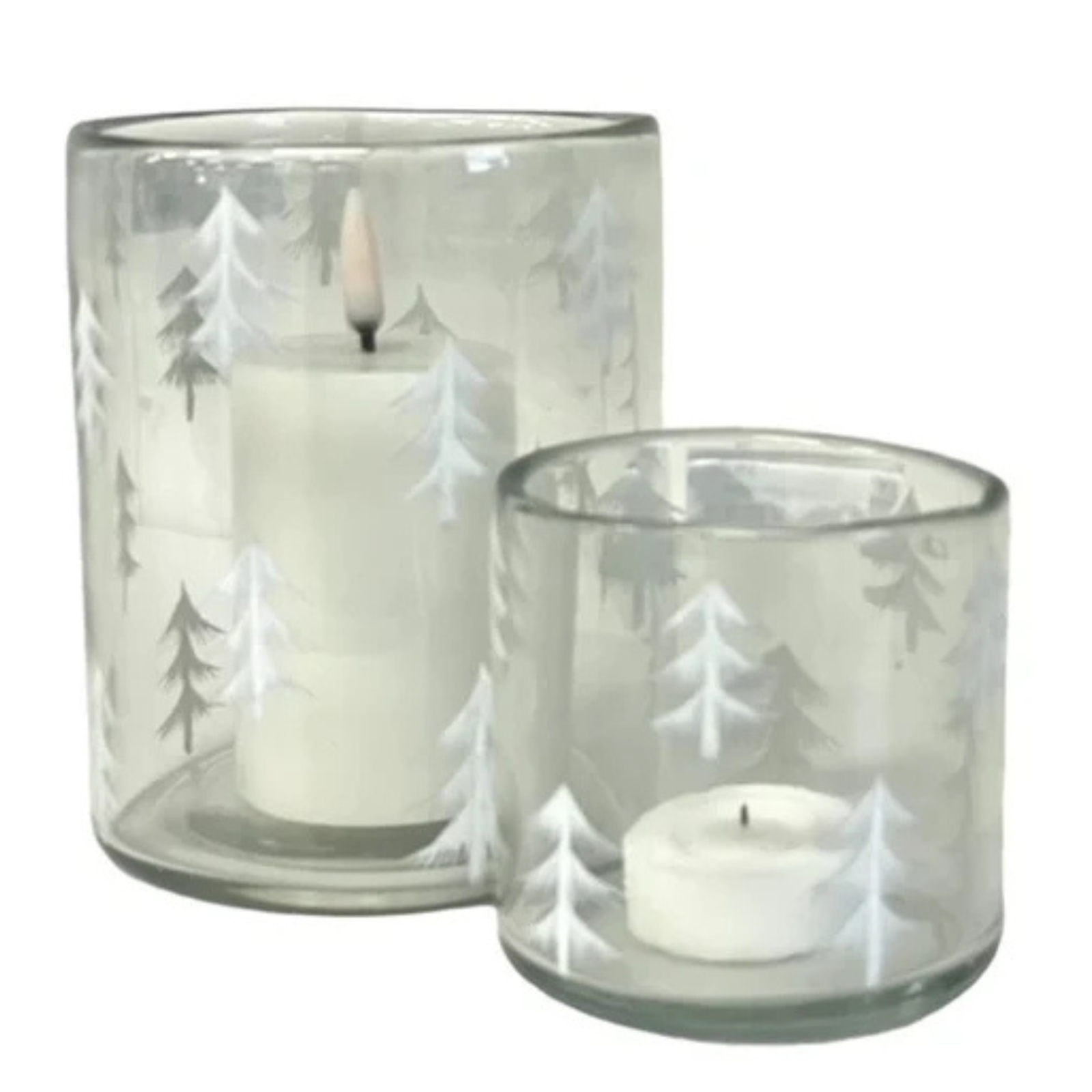 A white pillar candle lit inside a clear glass holder decorated with white etched pine tree silhouettes, shown against a plain white background.