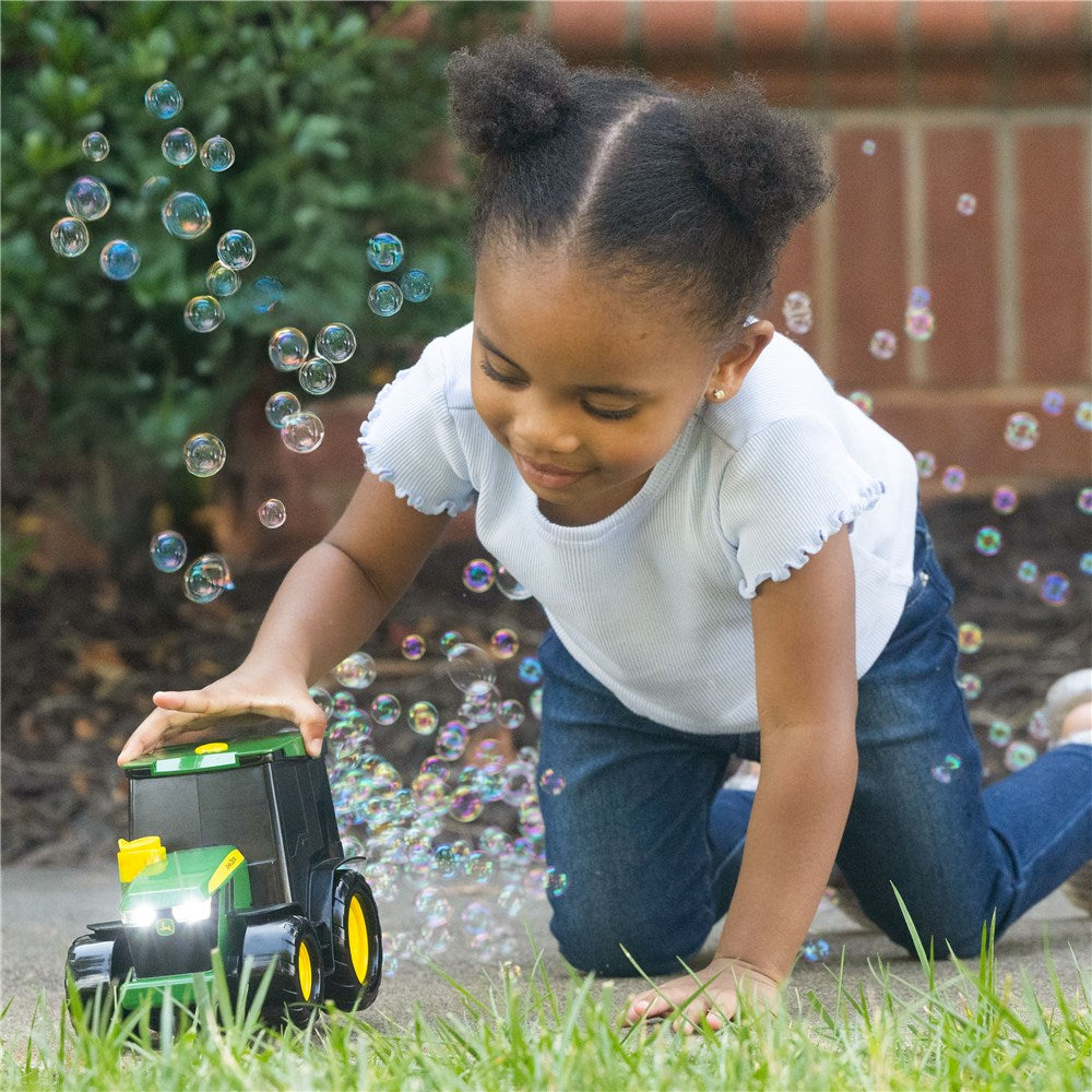 Child playing with a toy truck in a grassy area with bubbles