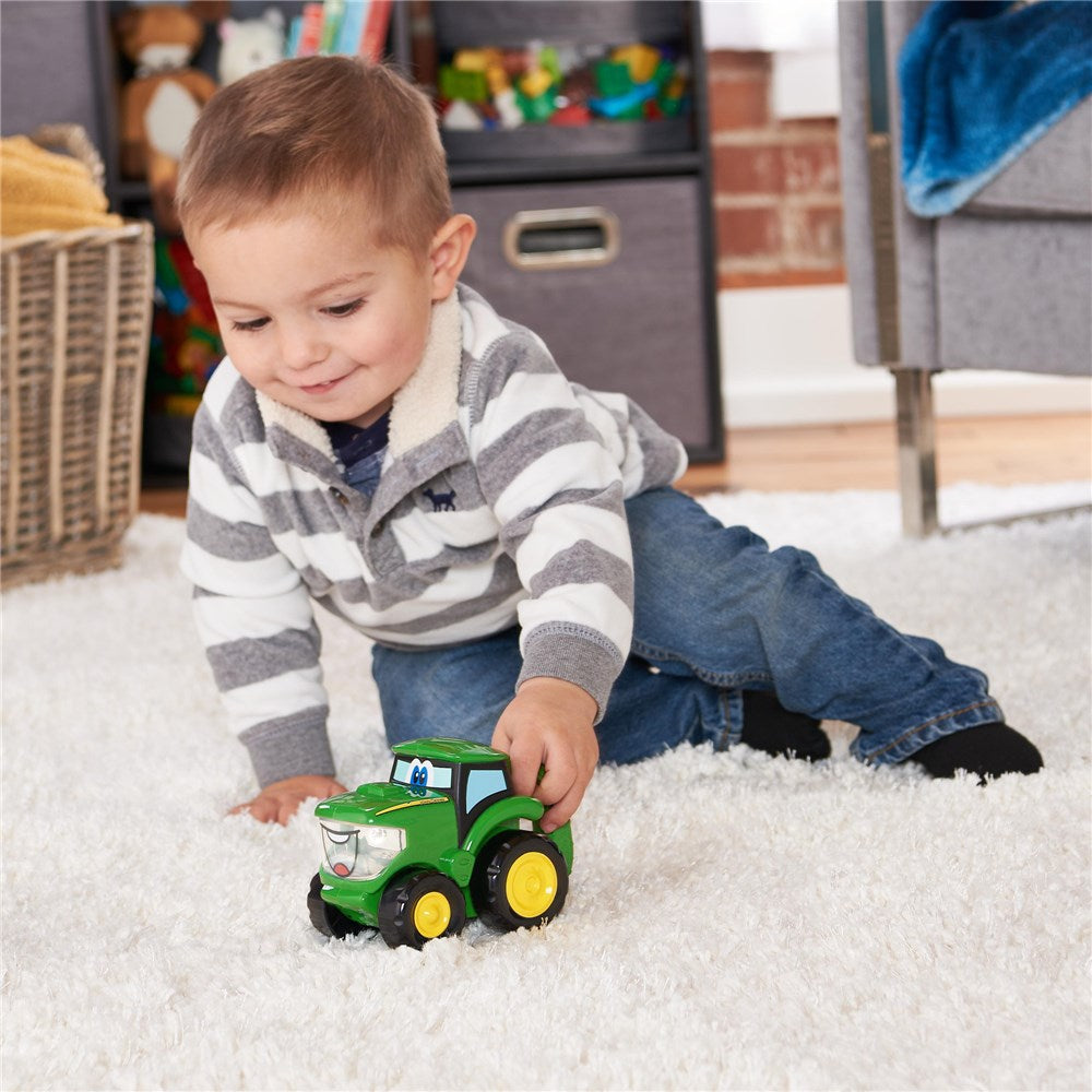 Child playing with a toy tractor on a carpeted floor