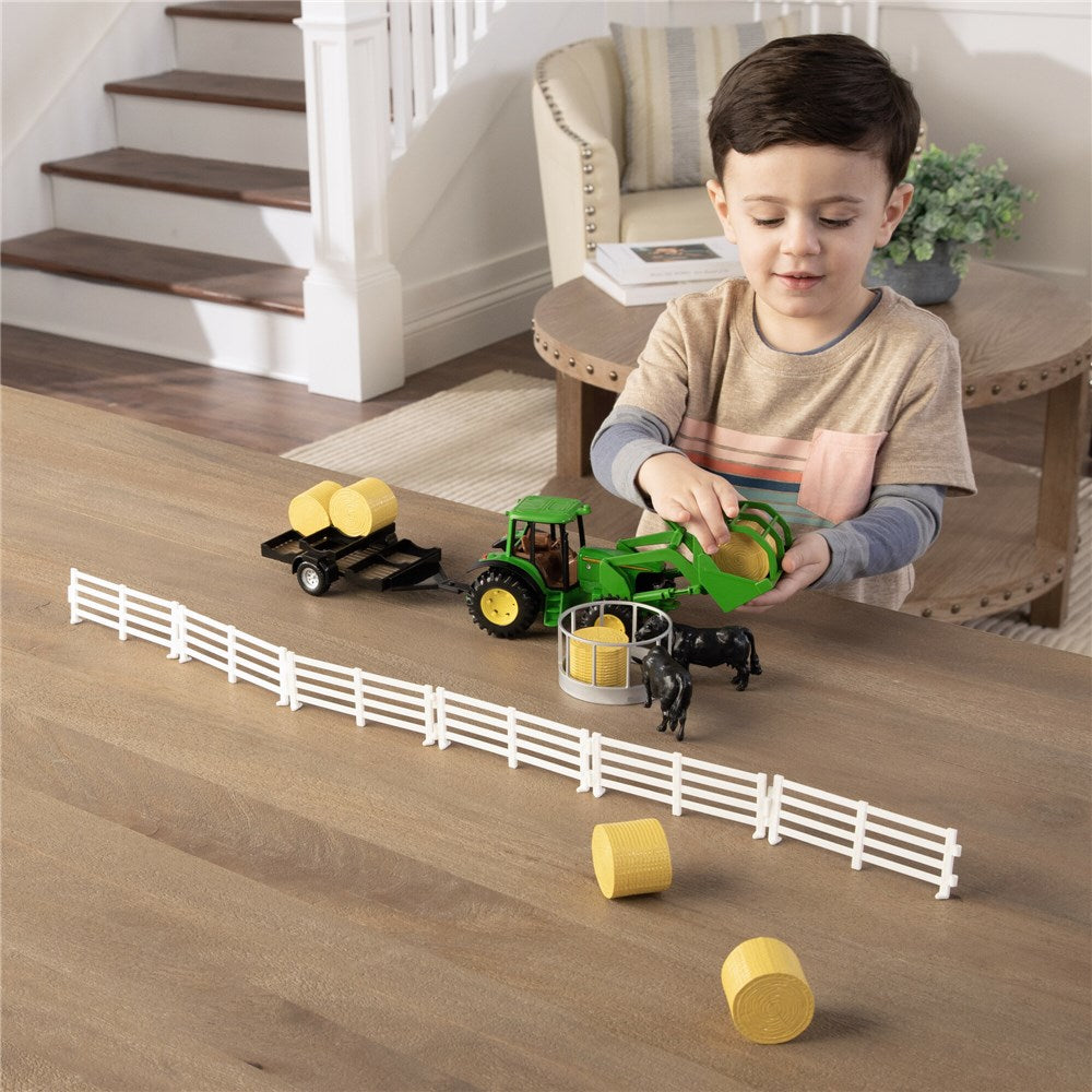 1:32 John Deere Hay Farm Set. Child playing with toy tractor and animals on a wooden floor.