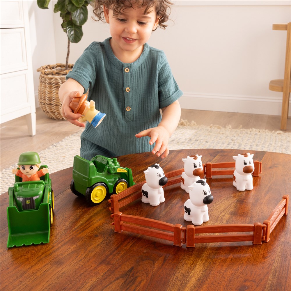 Child playing with toy farm set on a wooden floor