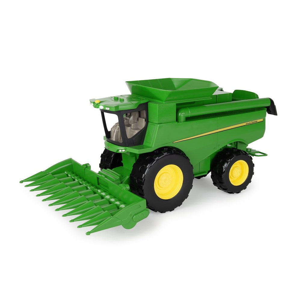 Toy combine harvester with green body and yellow wheels on a white background