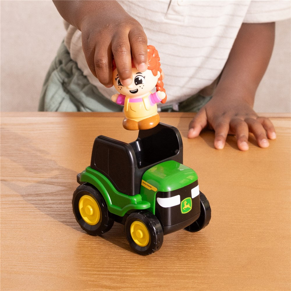 Child playing with a toy tractor and character on a wooden surface