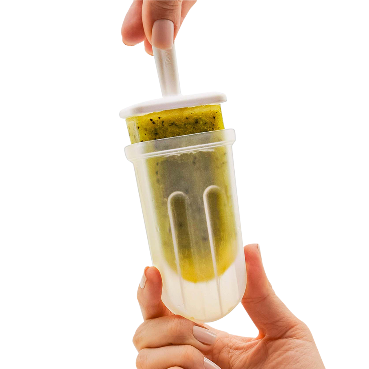 A hand holds a clear plastic popsicle mold while another hand inserts a white plastic stick into a green frozen dessert inside, against a solid white background.