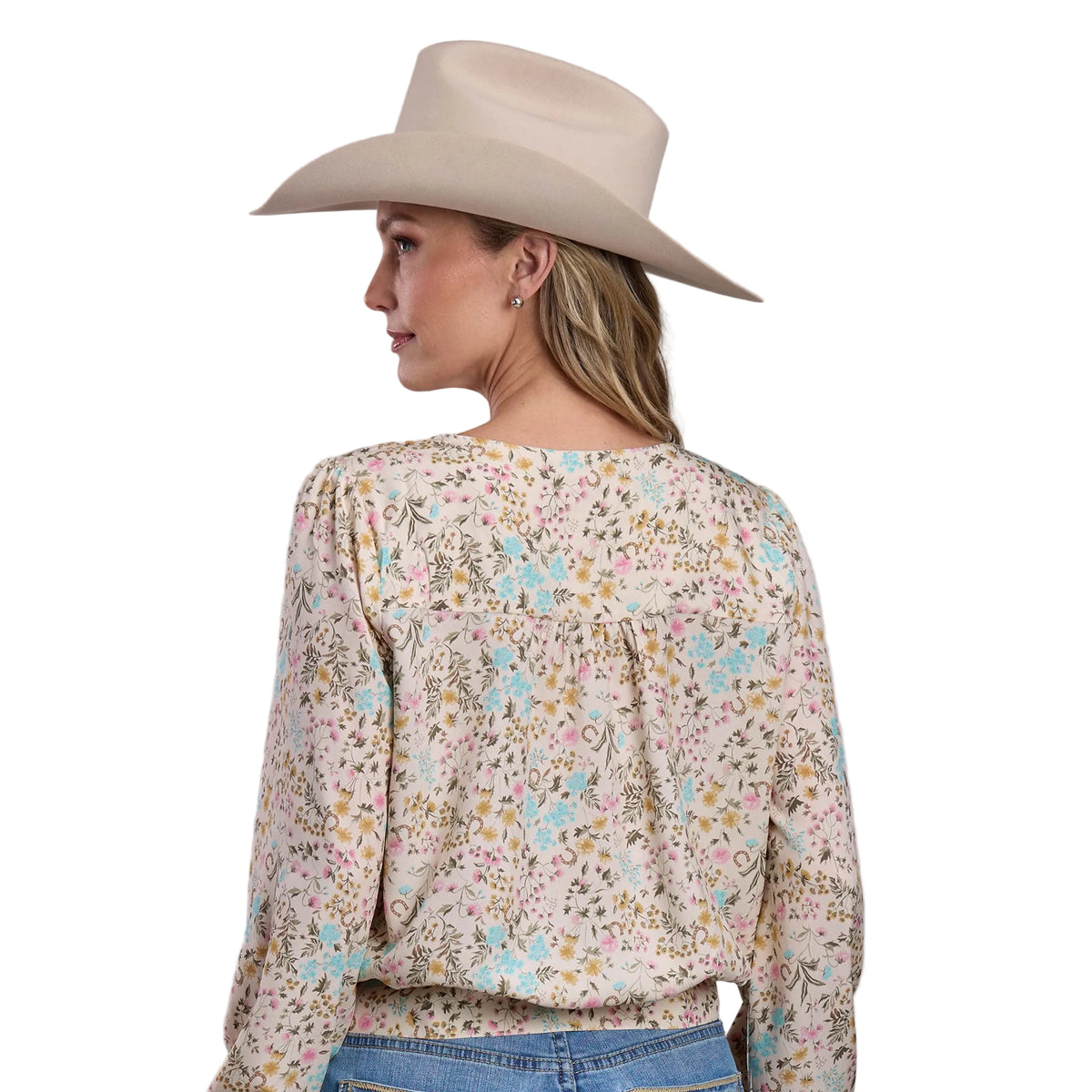 Woman wearing a floral blouse and beige cowboy hat on a plain background