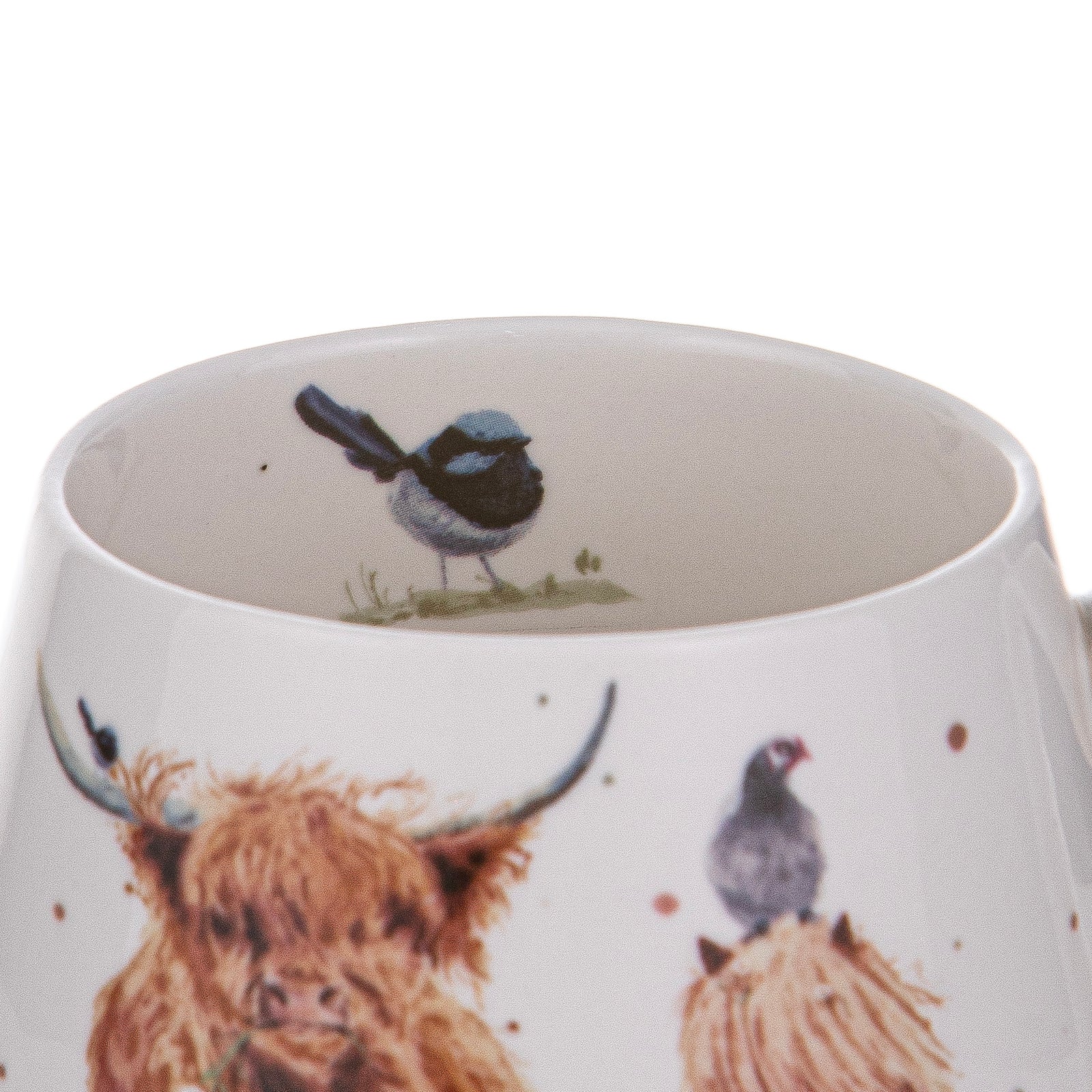 Close-up of a white ceramic mug featuring watercolor-style illustrations of a shaggy Highland cow, a small bird perched on its horn, and another bird on a hay bale, with the inside of the mug also showing a bird illustration.
