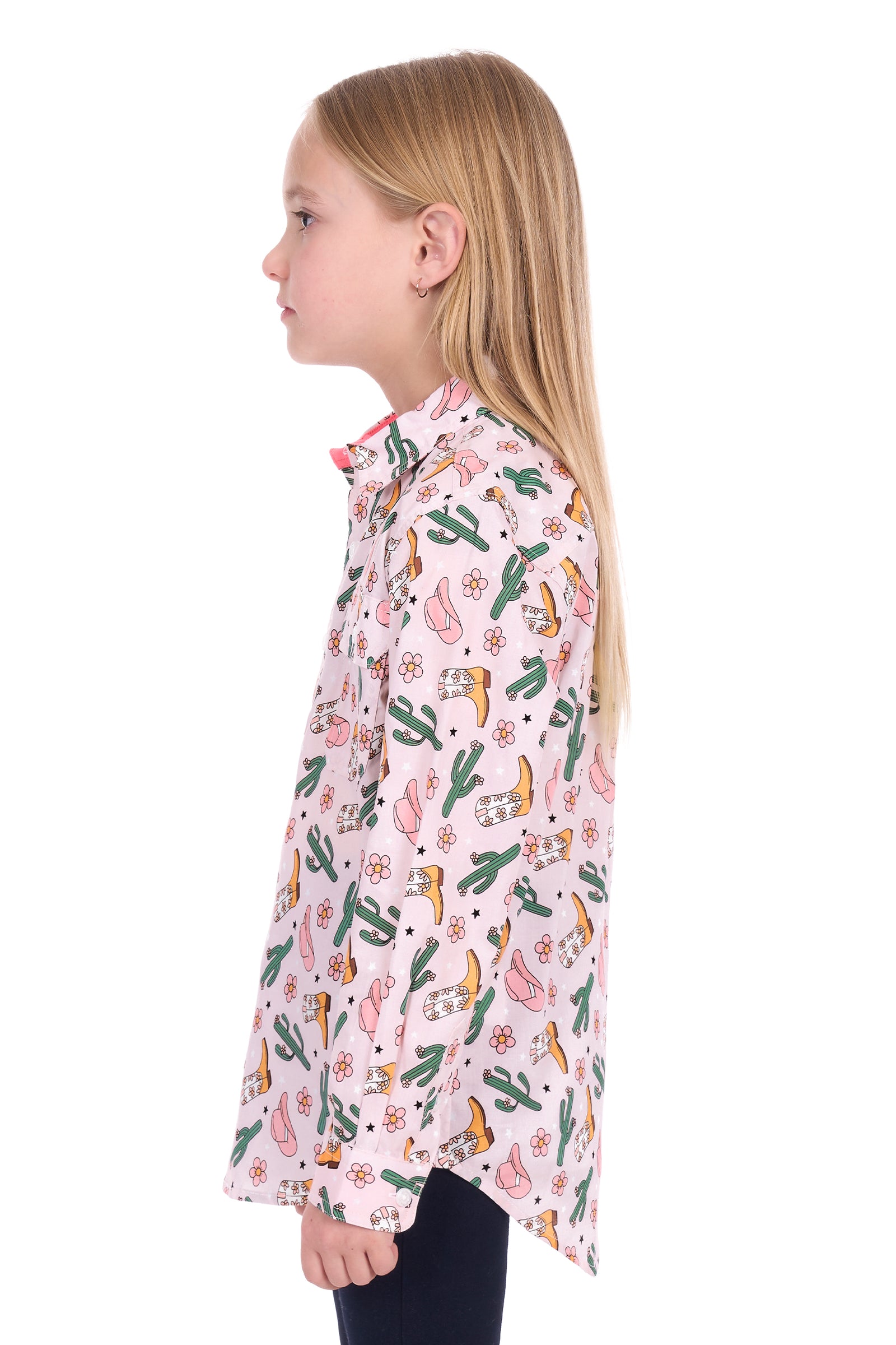 Young girl wearing a pink patterned shirt with cacti and boots on a white background