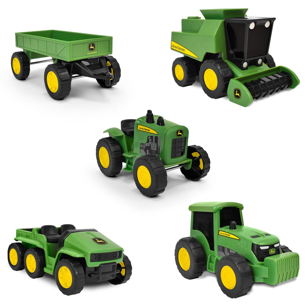 Set of green toy tractors and equipment on a white background