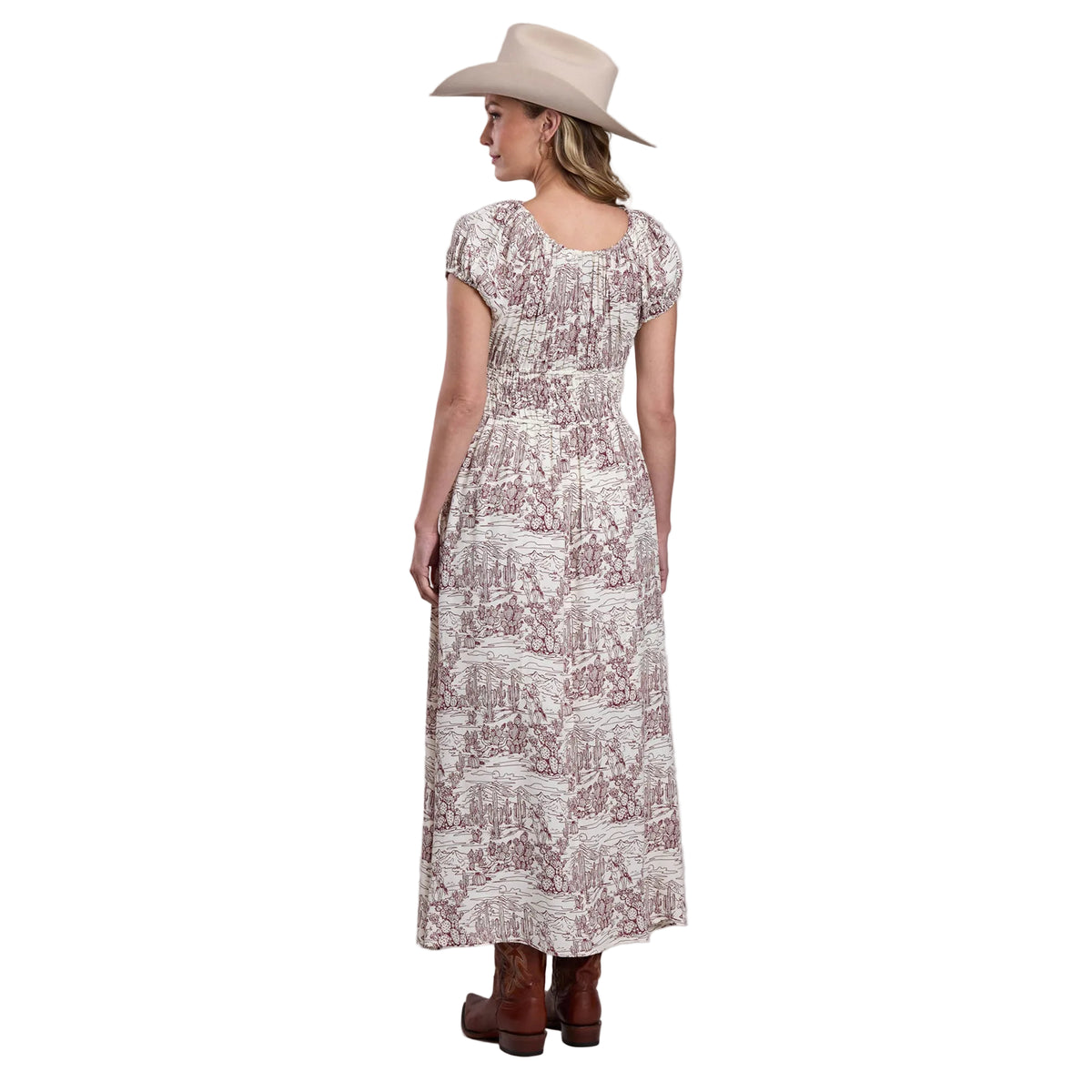 Woman wearing a patterned dress and cowboy hat on a plain background