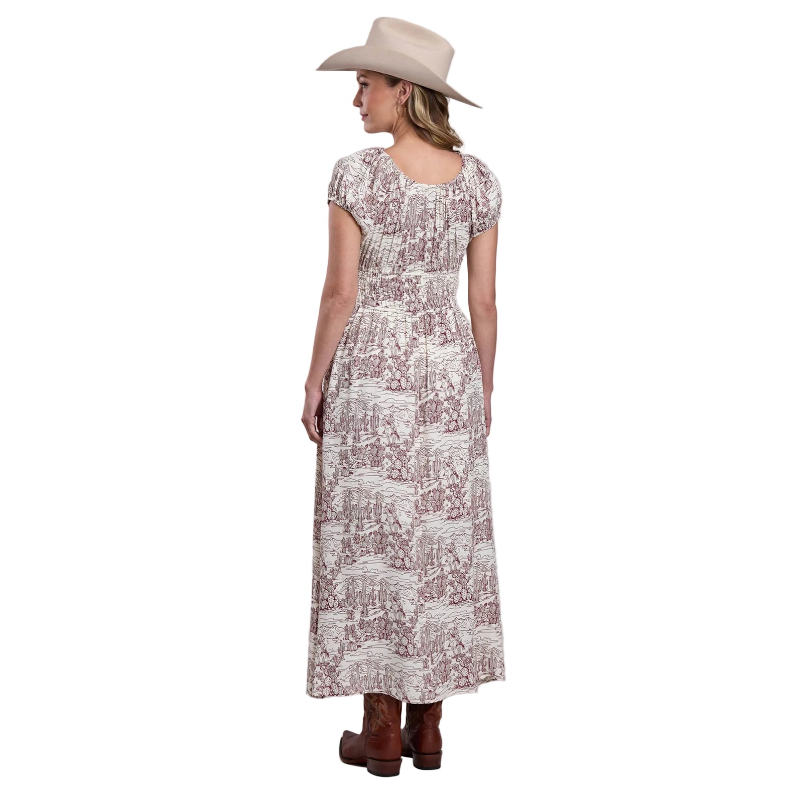 Woman wearing a patterned dress and cowboy hat on a plain background