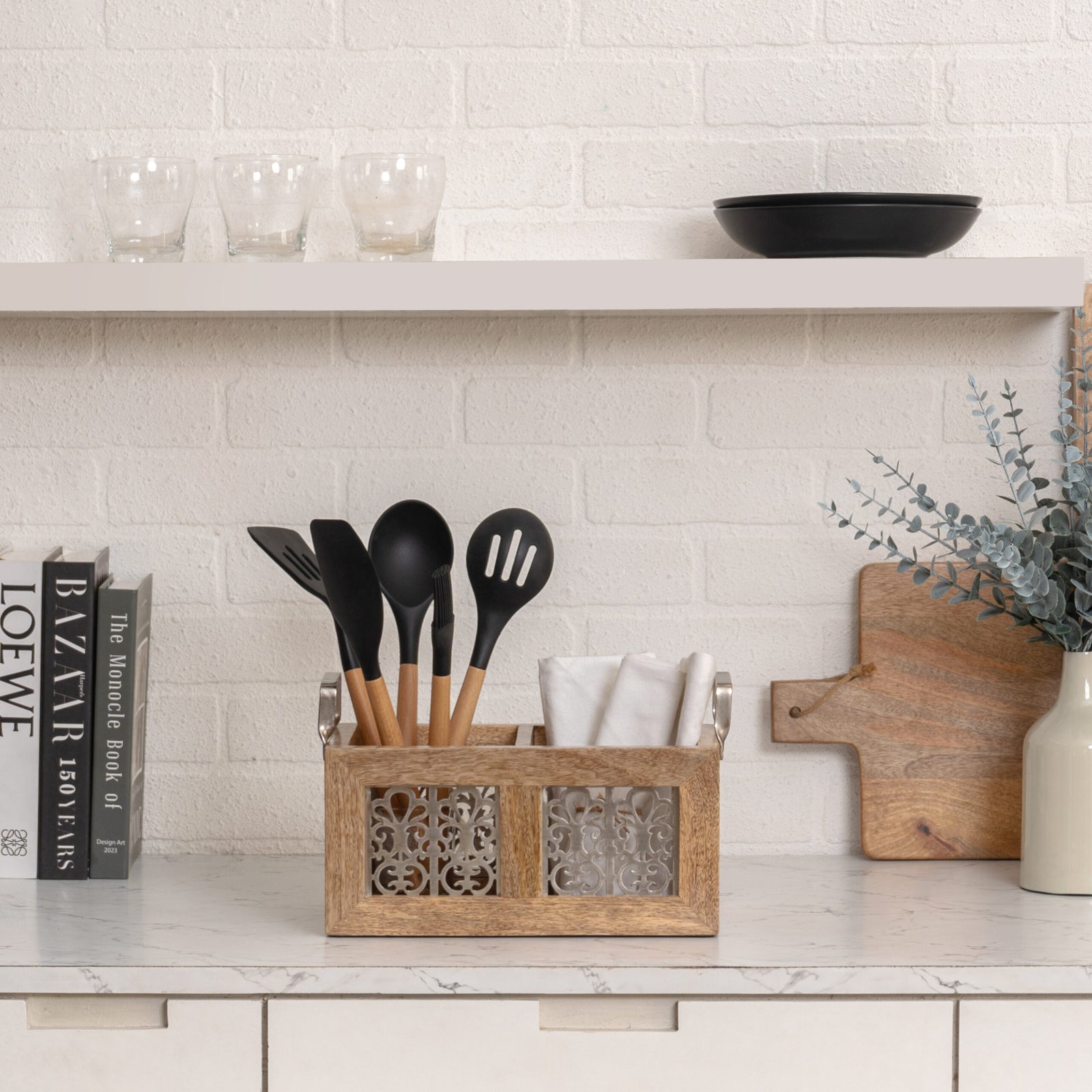 Handcrafted Mango Wood Cutlery Storage. Kitchen counter with utensil holder, cutting board, and books against a tiled wall.
