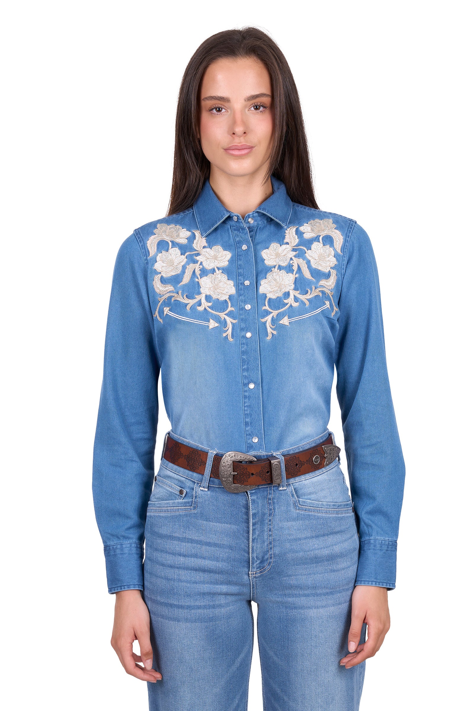Woman wearing a blue denim shirt with floral embroidery and jeans on a white background