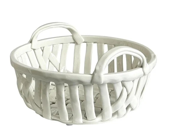 A white ceramic basket with two arched handles and a slatted open design, shown on a plain white background.