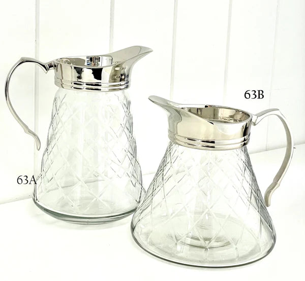 Two glass pitchers with silver lids on a white background