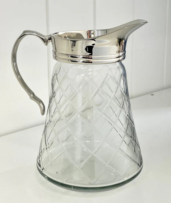 Clear glass pitcher with silver rim and handle on a white background