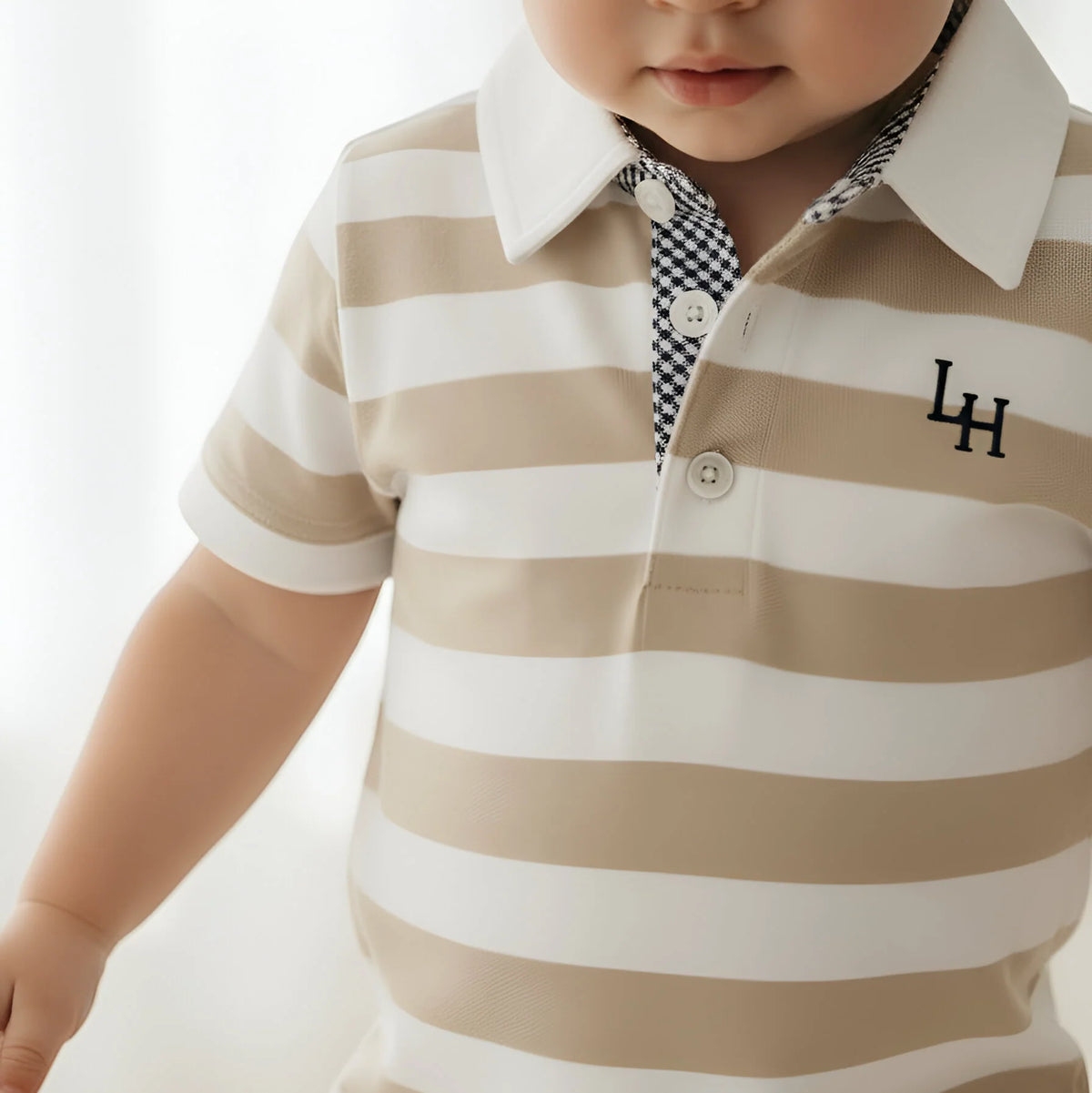 Child wearing a beige and white striped polo shirt with a logo on a light background