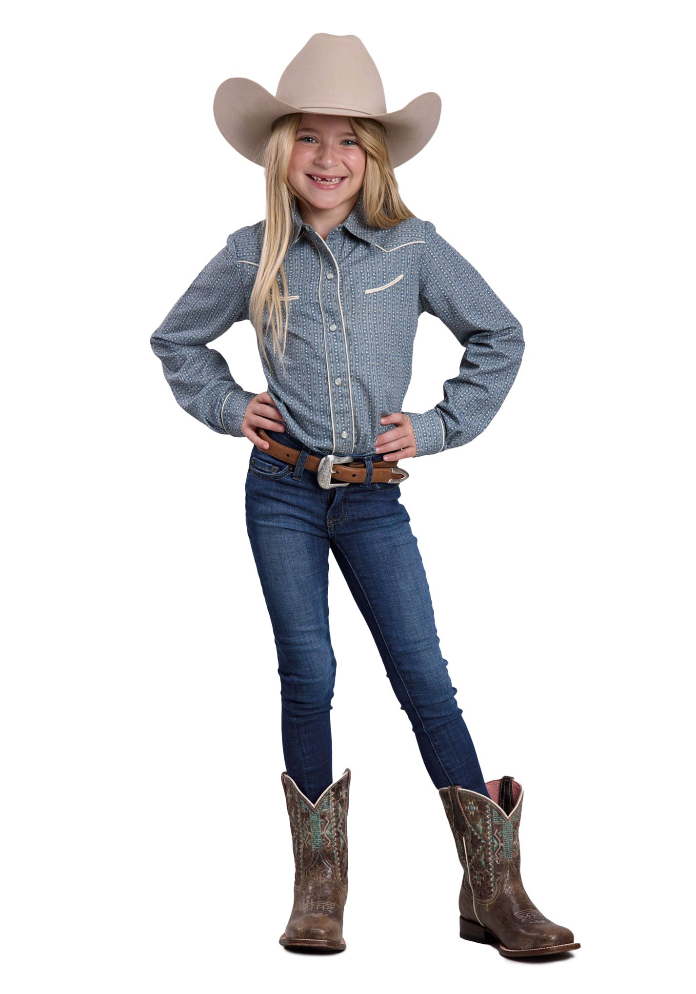 Young girl in cowboy attire with a blue shirt, jeans, and brown boots on a white background