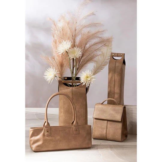 Harley Latte Lunch Bag. Three brown leather bags and a vase with flowers on a light background