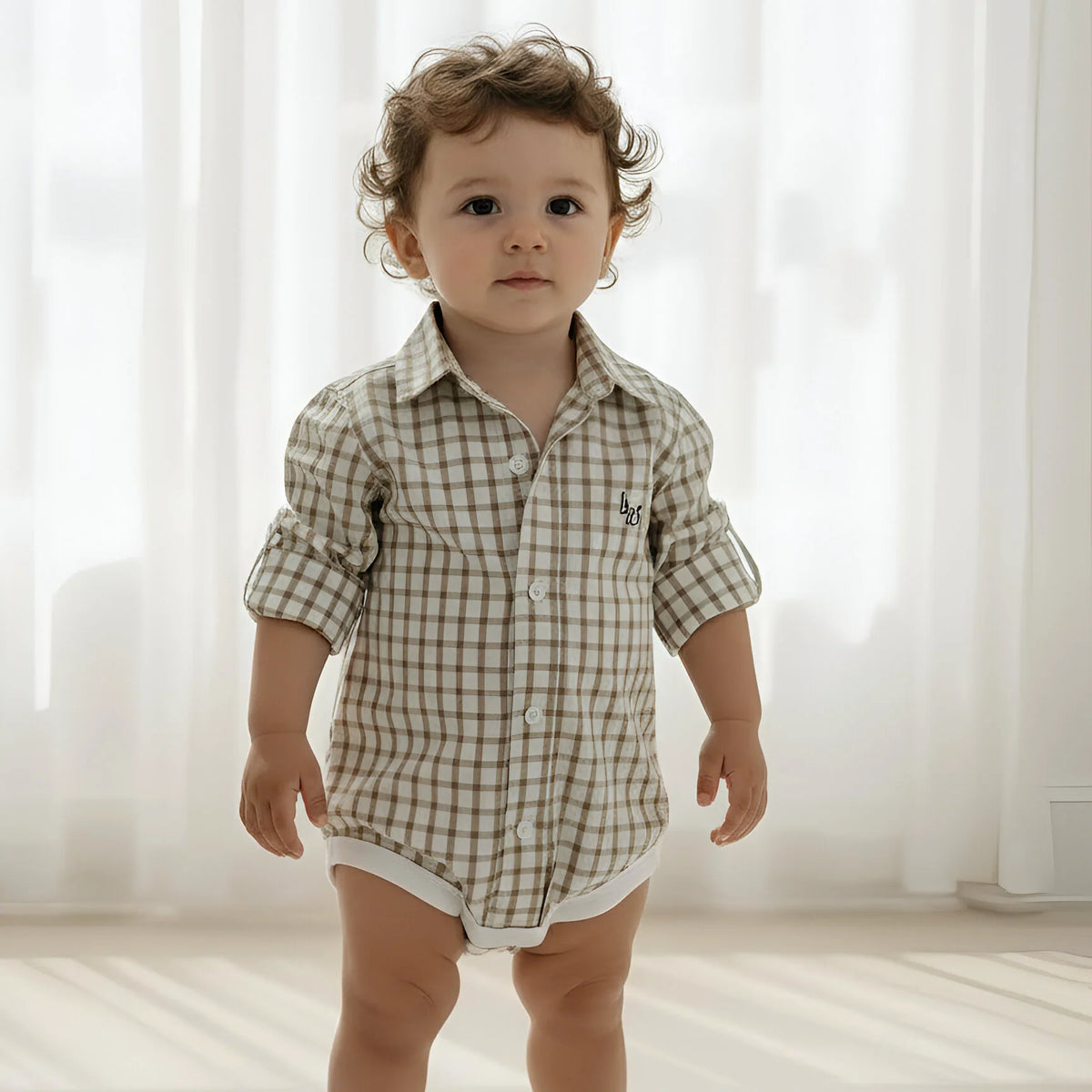 Child wearing a checkered shirt and shorts standing in a softly lit room.