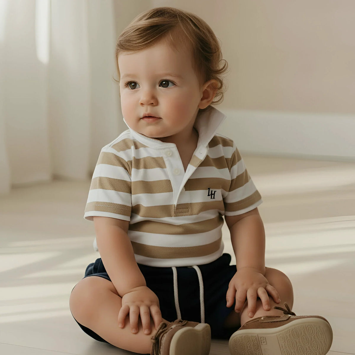 Child wearing a striped shirt and sitting on a light-colored floor.