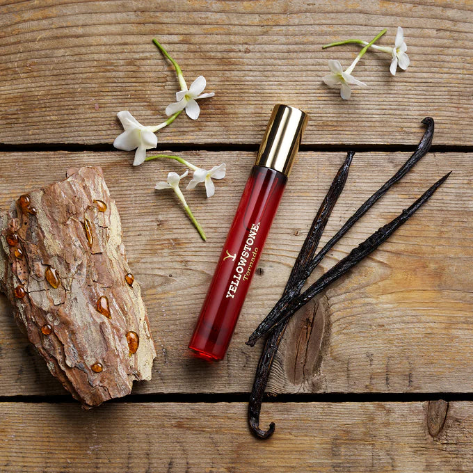 Yellowstone lip balm with vanilla beans and flowers on a wooden surface