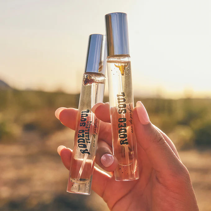 Two small perfume bottles held in a hand with a blurred natural background