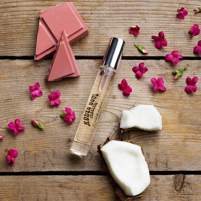 Skincare product with coconut pieces and pink flowers on a wooden surface