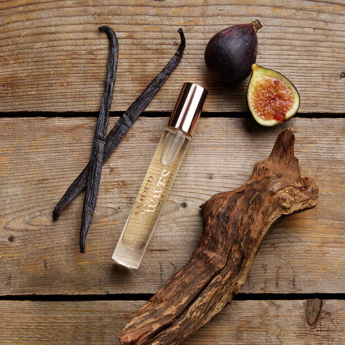 Perfume bottle with vanilla beans, figs, and wood on a wooden surface