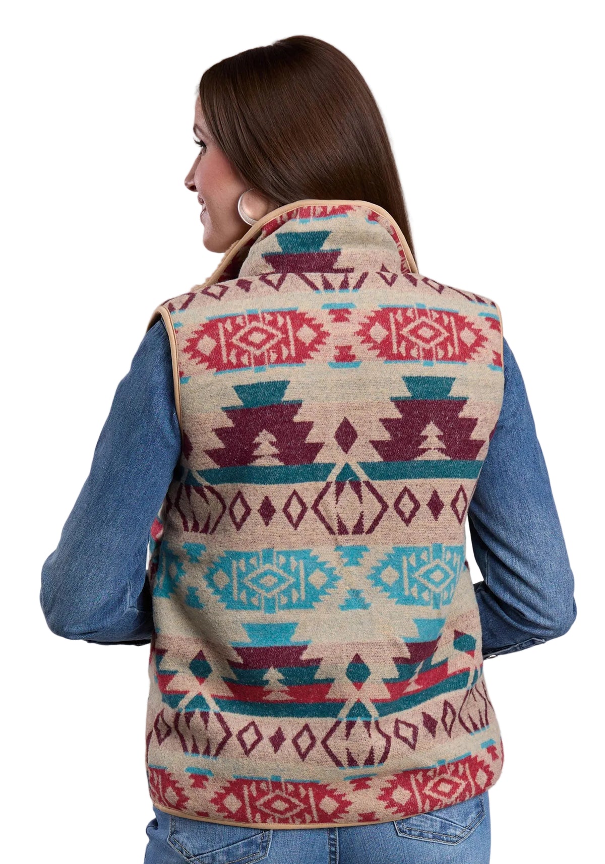 Woman wearing a patterned vest with a blue shirt underneath on a gray background