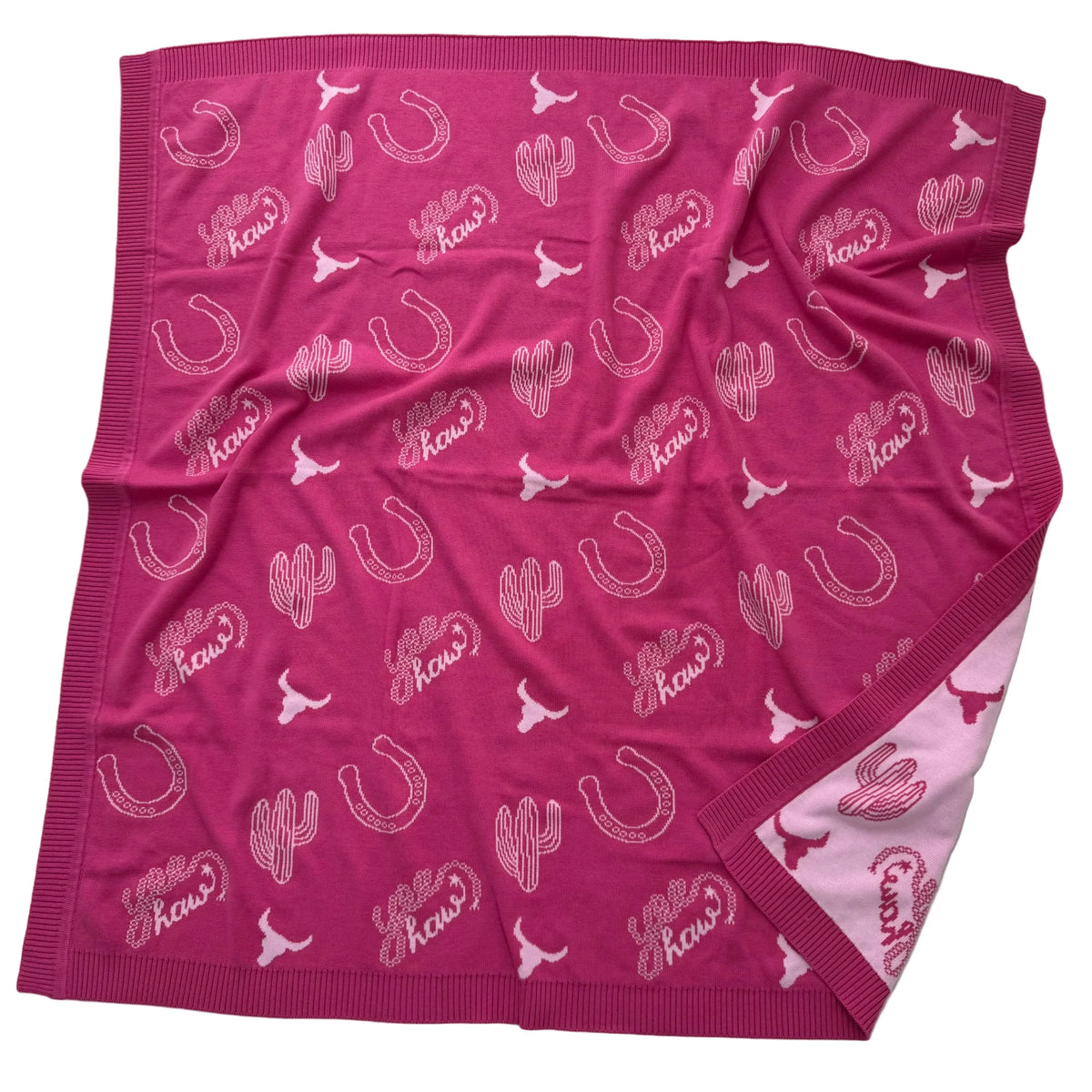 A pink fleece throw blanket featuring a repeating pattern of white horseshoes, cacti, longhorns, and the word 'Kows' in stylized script. The blanket is laid flat on a white background, showing its ribbed knit borders and a lighter pink reverse side.