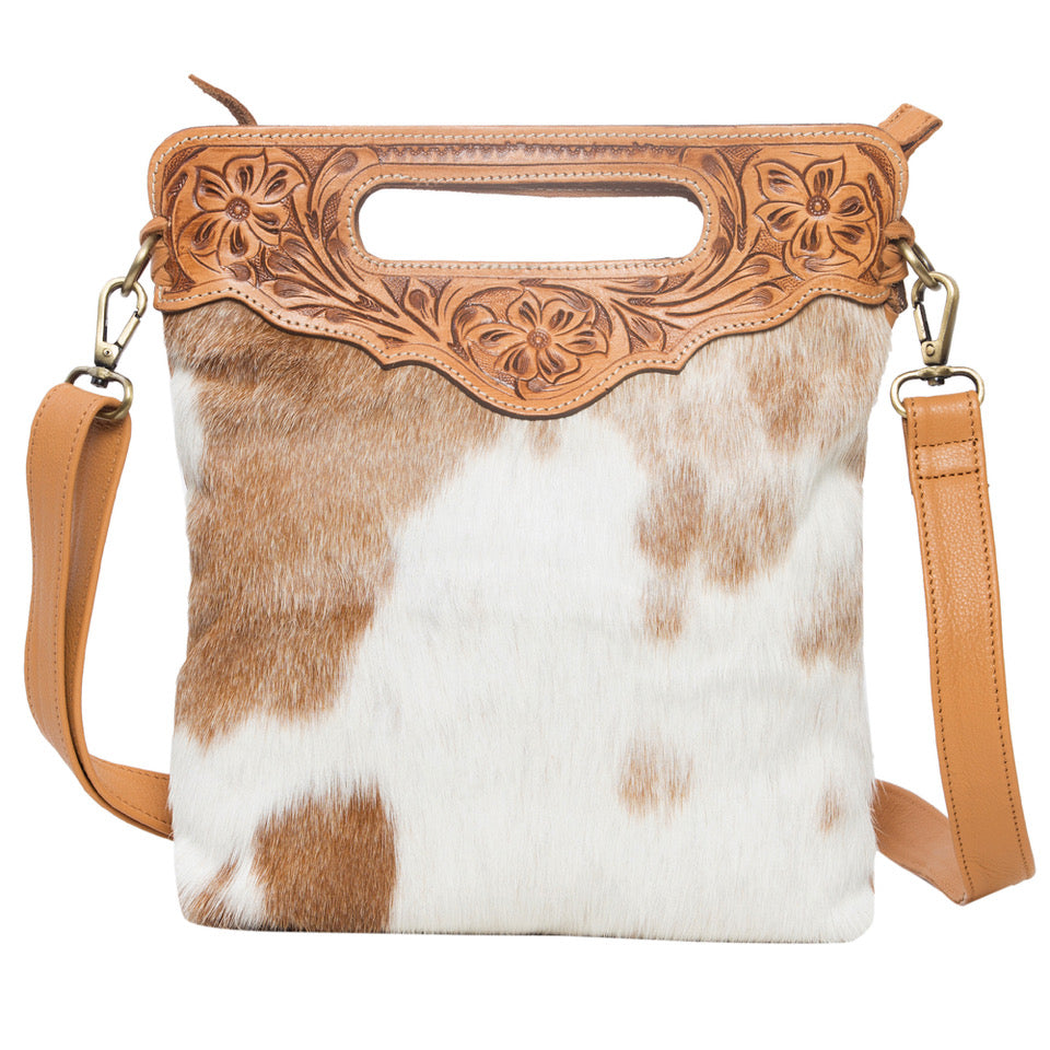 Cali Tan Tooling Leather Sling Cowhide Bag. Cowhide leather handbag with decorative brown leather handle on a white background