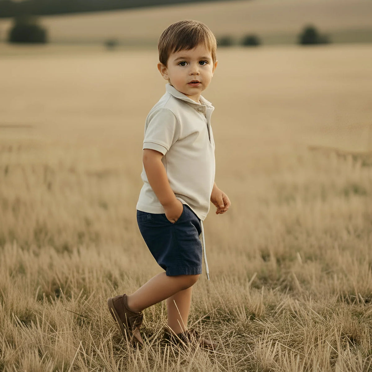 Young boy standing in a field with rolling hills in the background