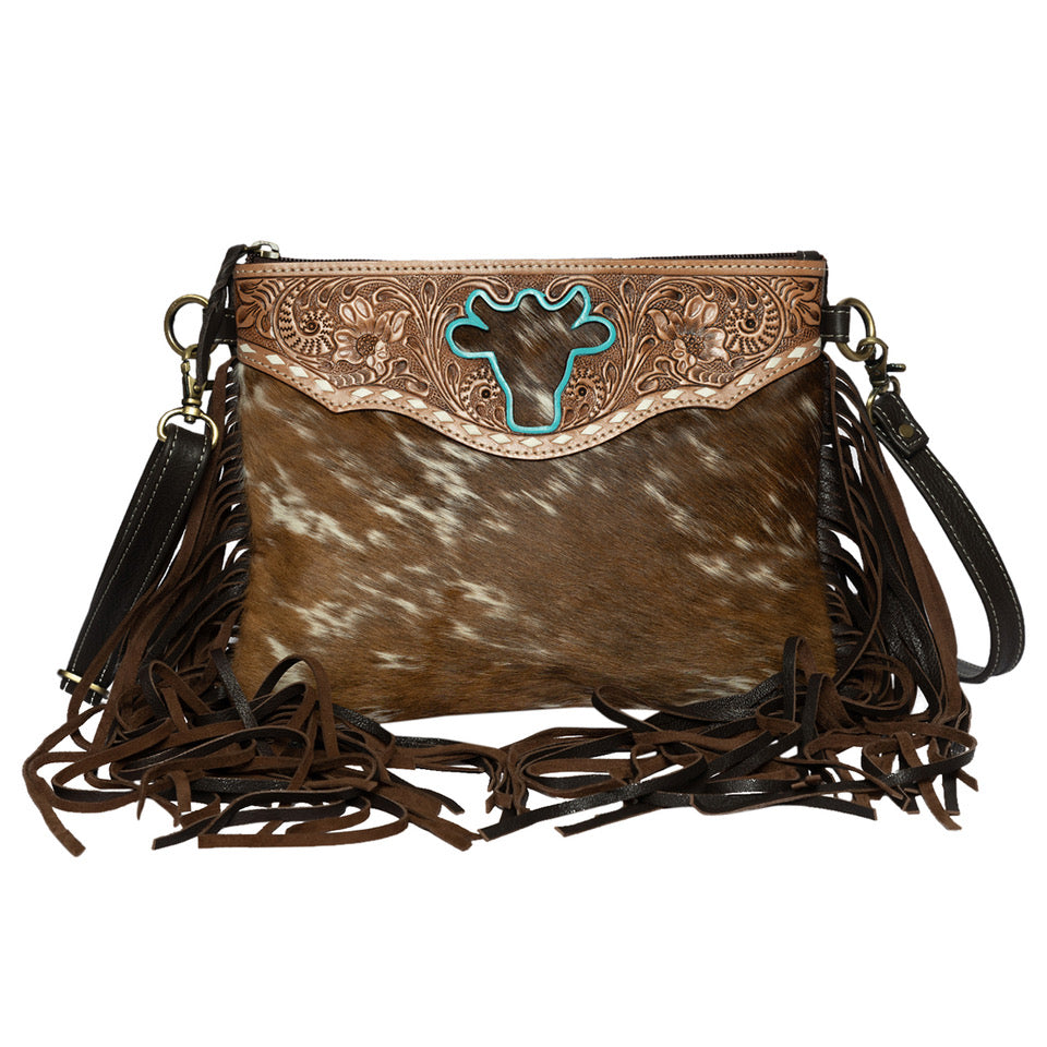 Women's Marbella Bullhead Cowhide Sling Bag with Fringes. A woman's sling bag with a fringed design and intricate hand carving, showcasing a beige and brown color scheme.