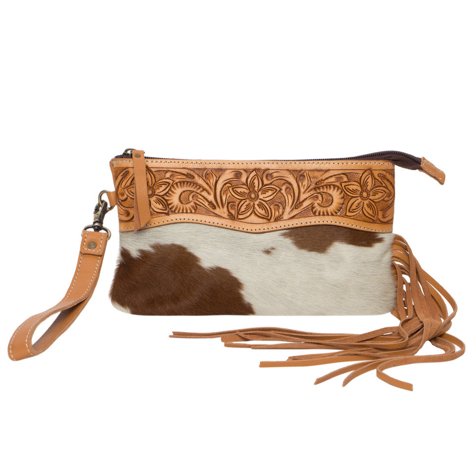 Salvador Tooling Leather Tassel Clutch. Brown and white cowhide clutch with floral tooled leather strap on a white background