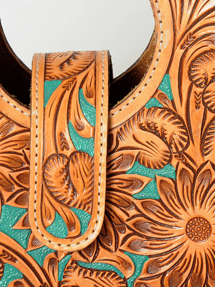 Close up of tooled American Darling western handbag with turquoise accents on a white background.