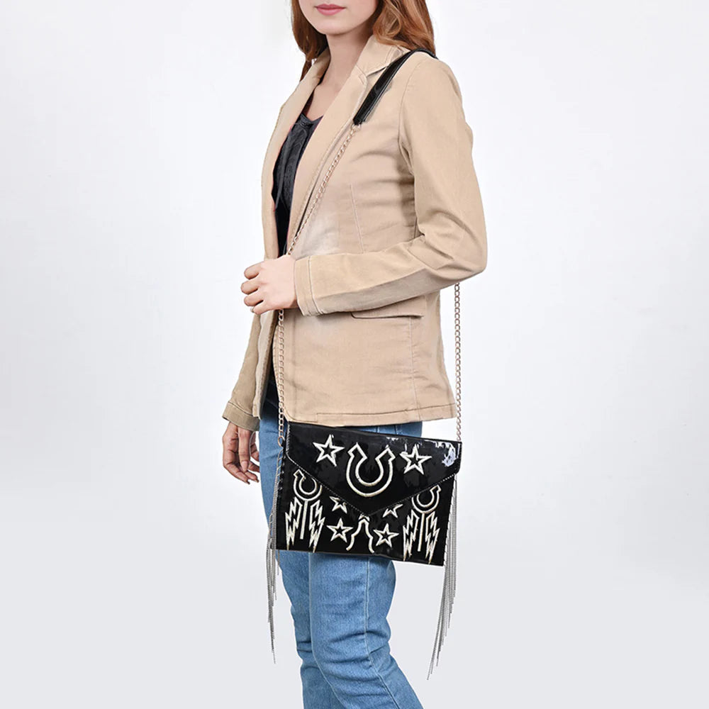 American Darling Rock & Roll Western Handbag. Woman holding a black handbag with white designs against a white background
