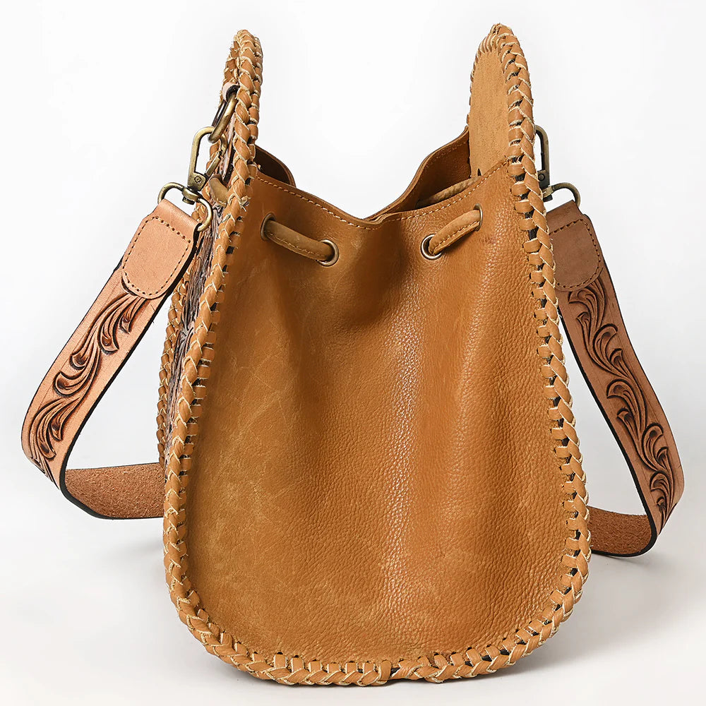 American Darling Western Floral Tooled Leather Sling Bag. Brown leather handbag with intricate designs on a white background